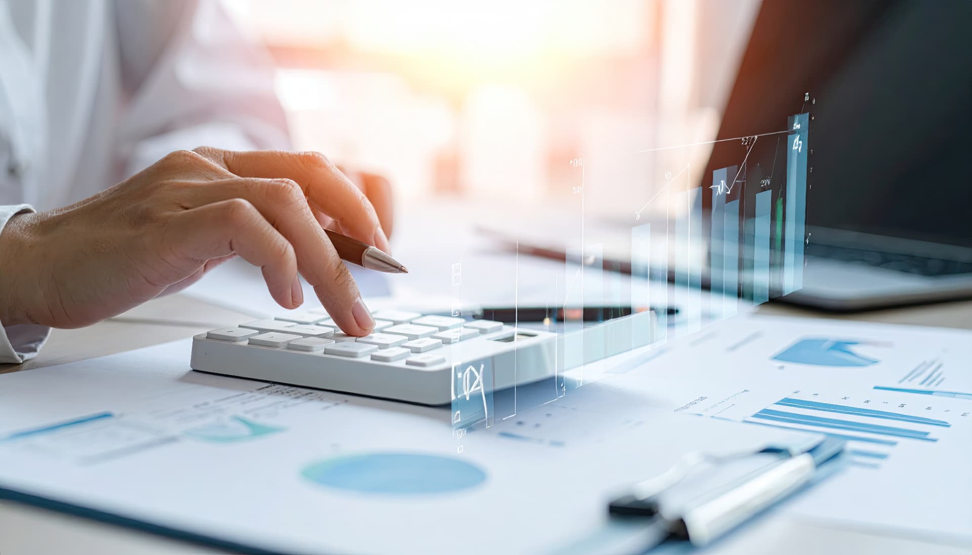 Professional using a calculator alongside financial charts and documents.