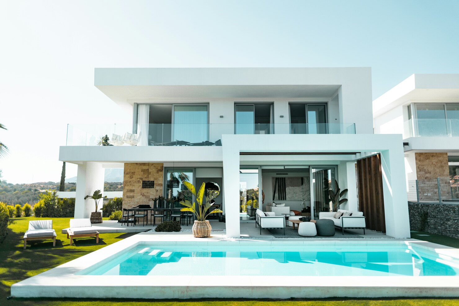 Modern white private residence with glass balconies, an open terrace and a swimming pool.