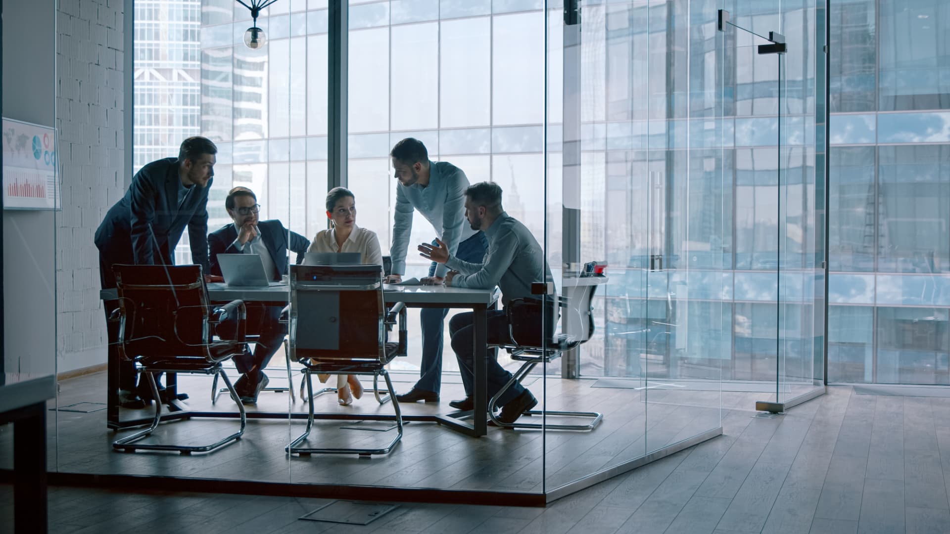 Business professionals meeting in a modern glass-walled office.