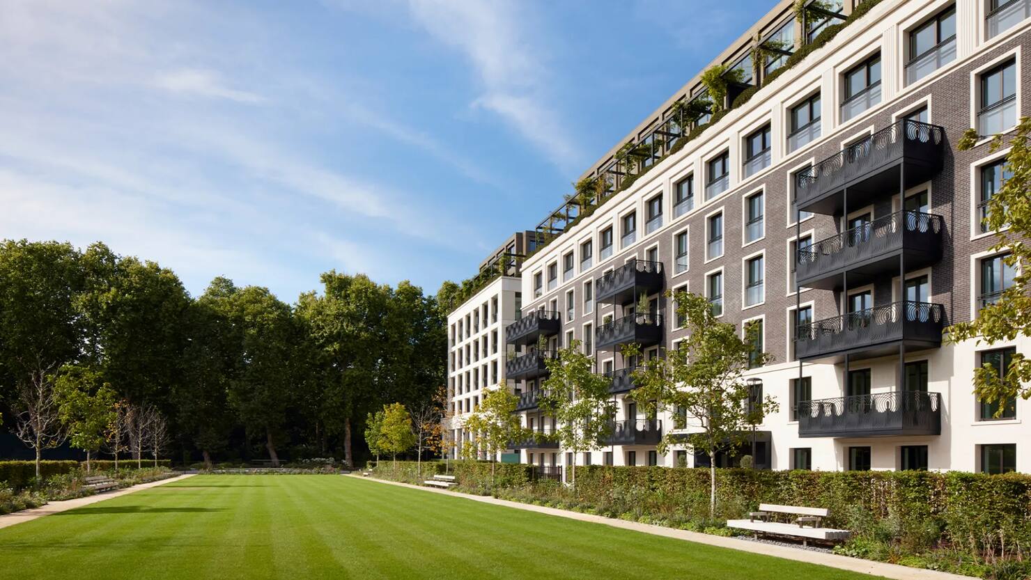 Apartment buildings at Chelsea Barracks in Belgravia, London, seen across a landscaped garden square and lawn.