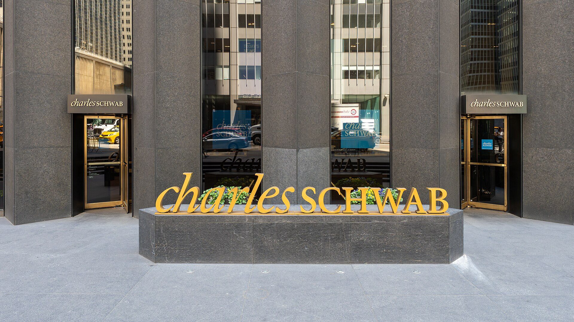 Charles Schwab branch entrance in New York with the company's gold lettering above the doorway