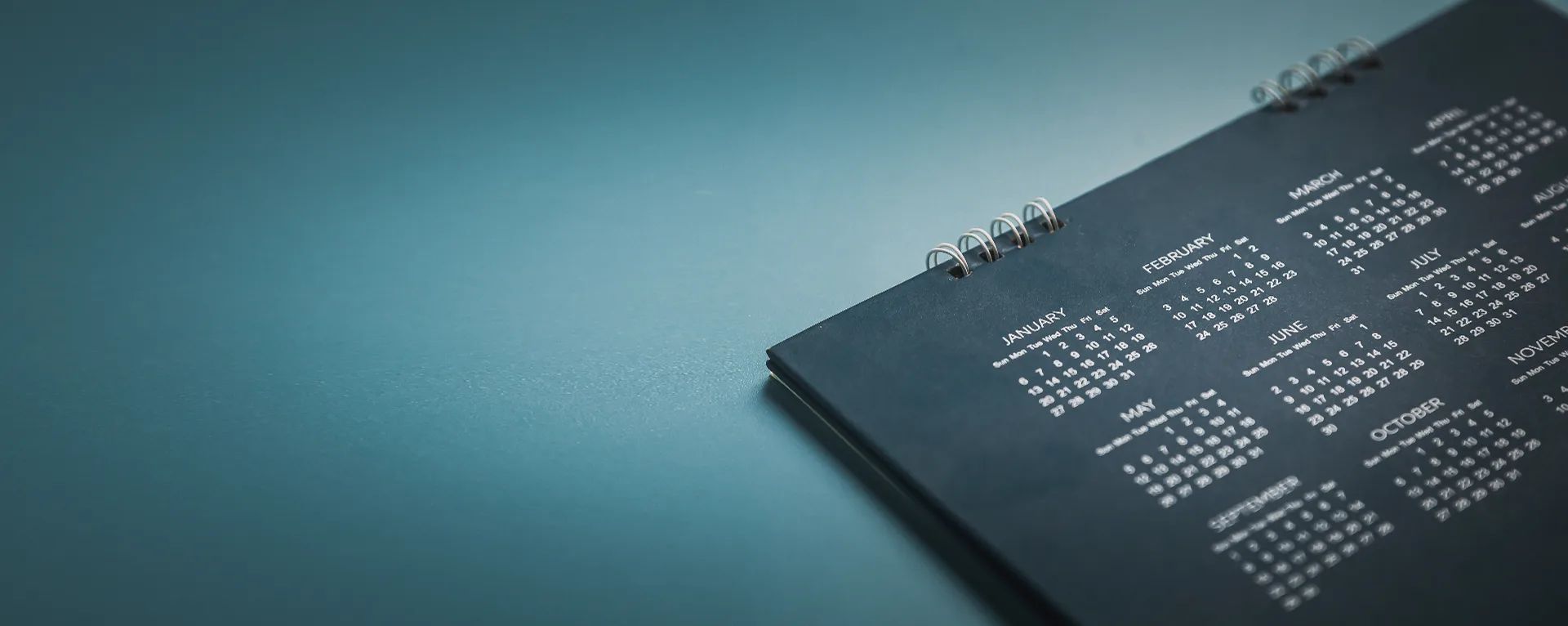 Desk calendar on a teal surface — UK Private Wealth Magazine editorial calendar