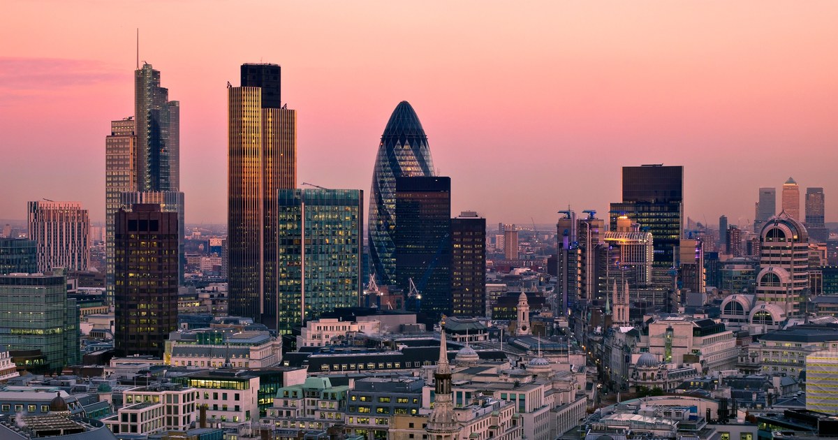 City of London skyline at dusk, with 30 St Mary Axe (the Gherkin) and surrounding financial district towers reflecting the evening sky.