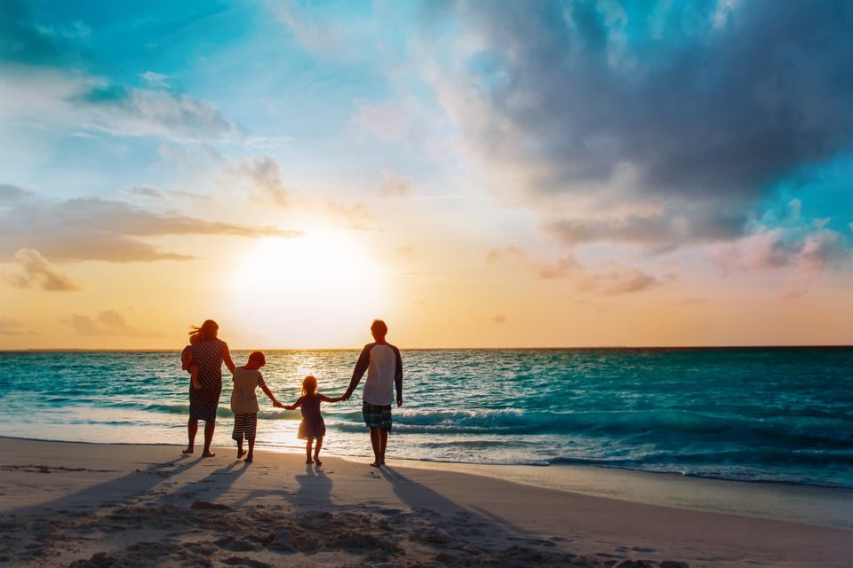 Family walking together by the sea at sunset