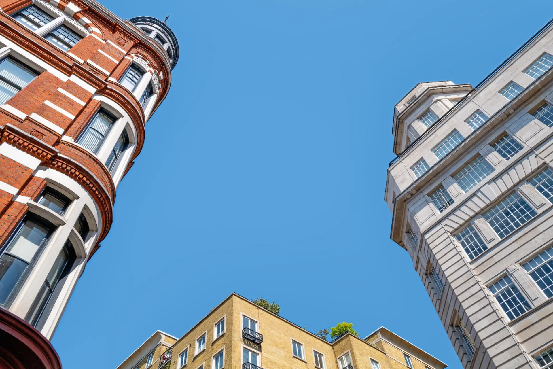 Classic London architecture viewed upward against a blue sky — UK Private Wealth Magazine