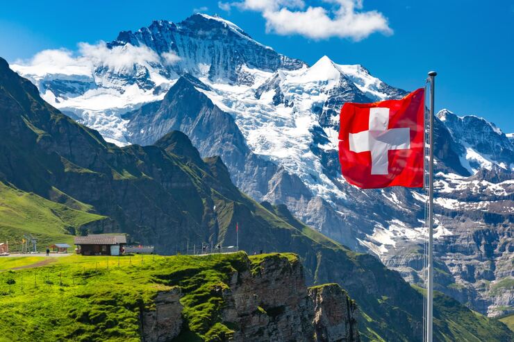 Swiss flag in front of Alpine mountains