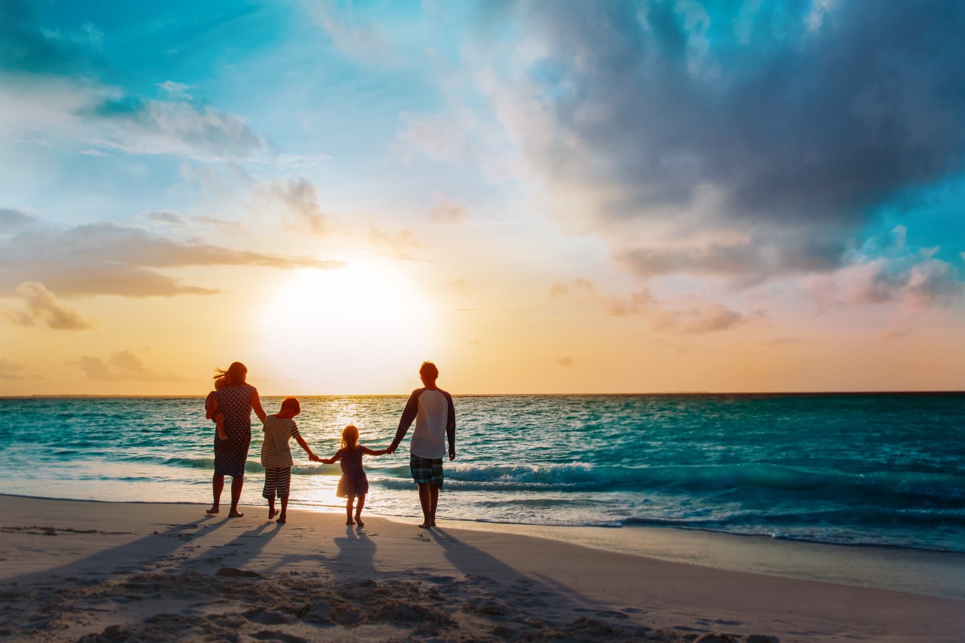 Family walking together by the sea at sunset